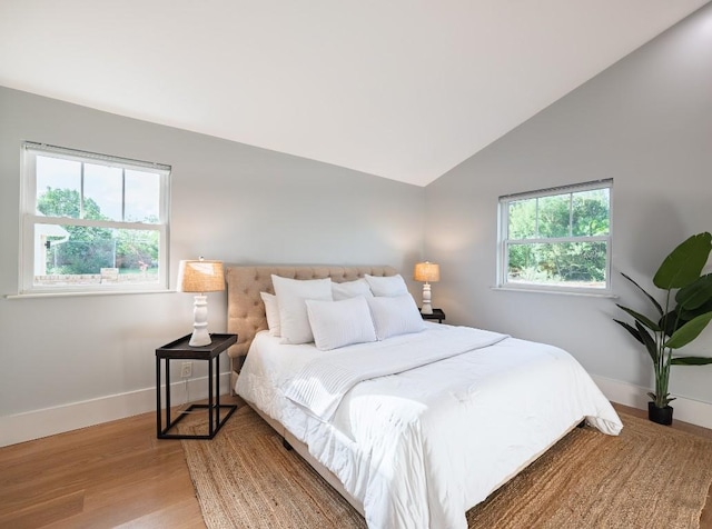bedroom with baseboards, lofted ceiling, and light wood finished floors