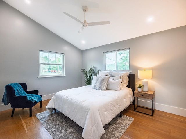 bedroom featuring baseboards, multiple windows, lofted ceiling, and light wood-style floors