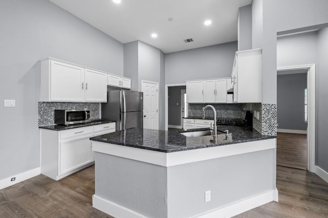 1214 Vargas Rd Unit B, Austin, TX 78741 - kitchen featuring appliances with stainless steel finishes, a peninsula, backsplash, white cabinets, and recessed lighting