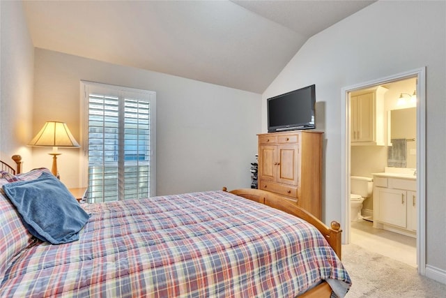 bedroom featuring ensuite bathroom, light colored carpet, and lofted ceiling