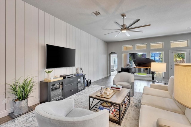 living room featuring baseboards, arched walkways, ceiling fan, and wood finished floors