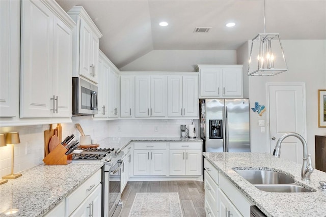 4229 Mercer Rd, Georgetown, TX 78628 - kitchen featuring appliances with stainless steel finishes, a sink, lofted ceiling, white cabinets, and a chandelier