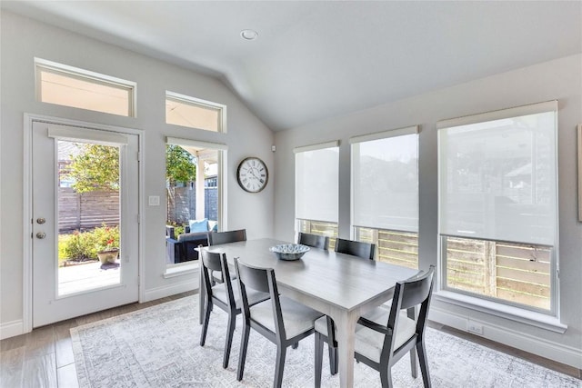dining room featuring light wood-style floors, baseboards, and vaulted ceiling