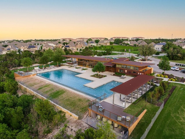 pool at dusk featuring a community pool, a patio, and a residential view