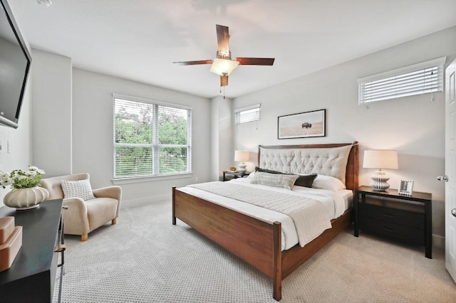 bedroom featuring baseboards, multiple windows, light carpet, and ceiling fan