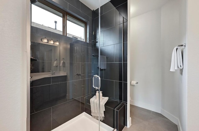 bathroom with a sink, baseboards, tile patterned flooring, and a shower stall