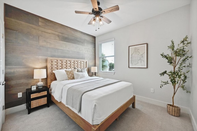 bedroom featuring baseboards, ceiling fan, wooden walls, and light carpet