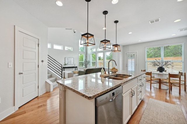 kitchen featuring stainless steel dishwasher, visible vents, a sink, and light wood-type flooring