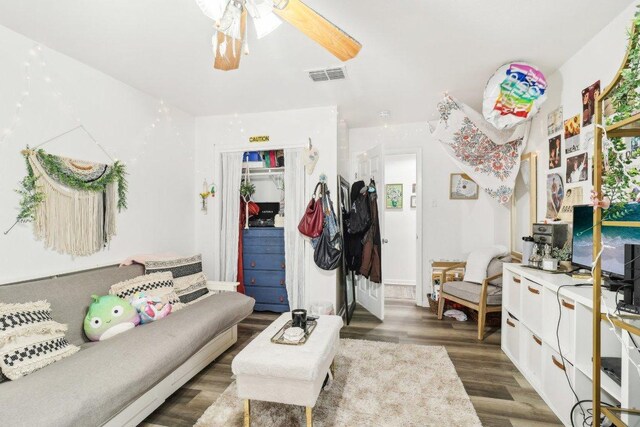 living area with visible vents, a ceiling fan, and wood finished floors