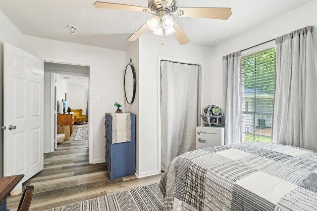 bedroom featuring baseboards, ceiling fan, a closet, and wood finished floors