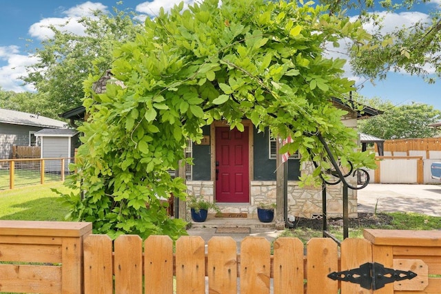 view of exterior entry featuring fence and stone siding