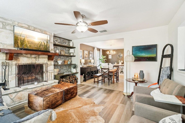 421 James St, Boerne, TX 78006 - living room with light wood-style flooring, ceiling fan, a chandelier, and a fireplace