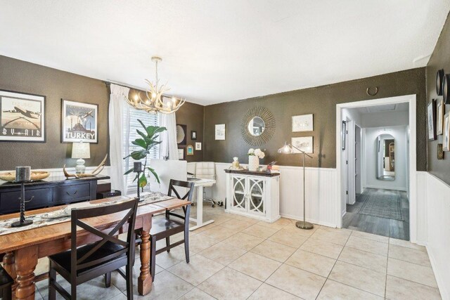 dining room with light tile patterned floors, wainscoting, and a chandelier