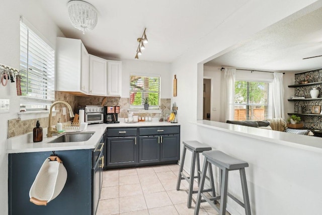 421 James St, Boerne, TX 78006 - kitchen featuring a sink, decorative backsplash, light countertops, light tile patterned floors, and white cabinetry