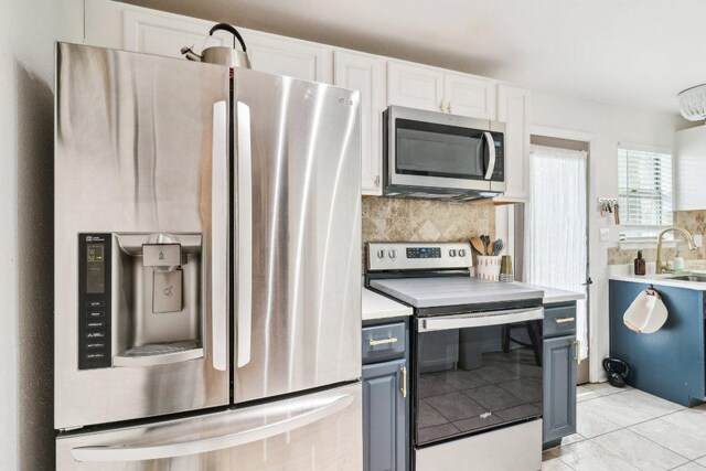 kitchen with light countertops, stainless steel appliances, decorative backsplash, and a sink