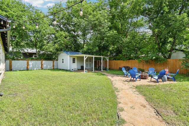 view of yard featuring an outdoor structure, a fire pit, and a fenced backyard