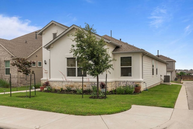 bungalow-style house with a shingled roof, stucco siding, central AC, and a front yard
