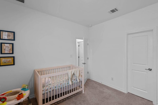 carpeted bedroom featuring a crib, baseboards, and visible vents