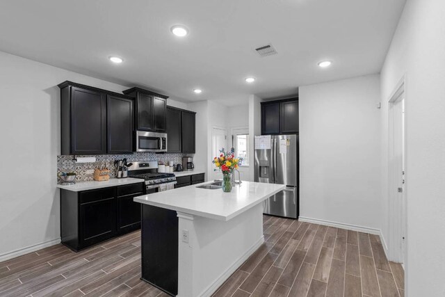 kitchen featuring backsplash, visible vents, appliances with stainless steel finishes, a sink, and dark wood-type flooring