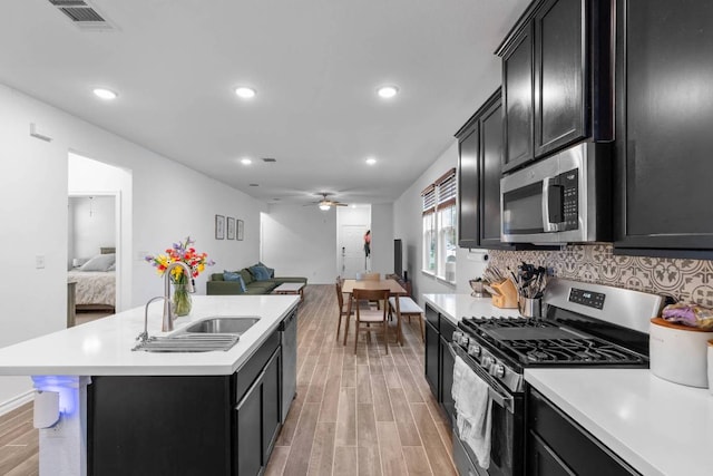 kitchen with a sink, dark cabinetry, stainless steel appliances, and open floor plan
