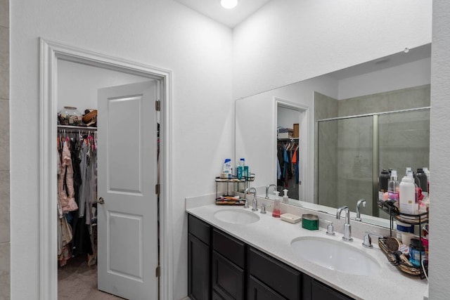 bathroom featuring double vanity, a sink, a walk in closet, and a stall shower