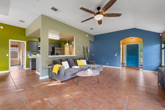 living area with light tile patterned flooring, arched walkways, visible vents, and a ceiling fan