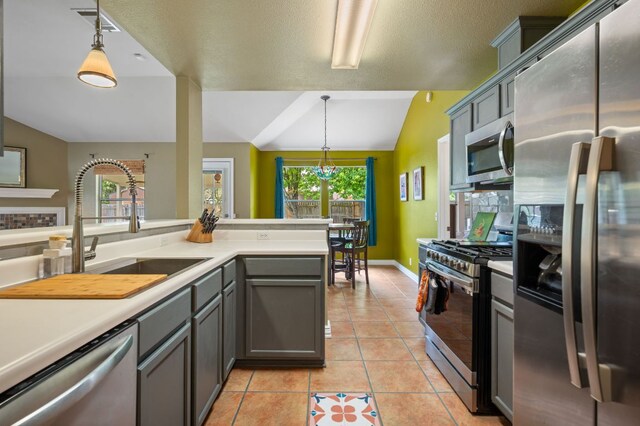 kitchen with lofted ceiling, light countertops, a sink, appliances with stainless steel finishes, and gray cabinetry