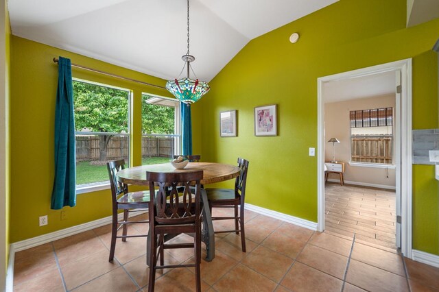 tiled dining space with baseboards and lofted ceiling