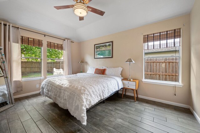 bedroom featuring baseboards, wood finish floors, and multiple windows