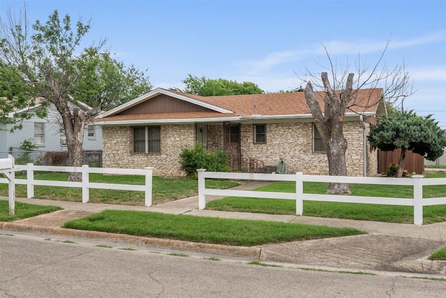 single story home featuring a chimney, a front lawn, a fenced front yard, and stone siding