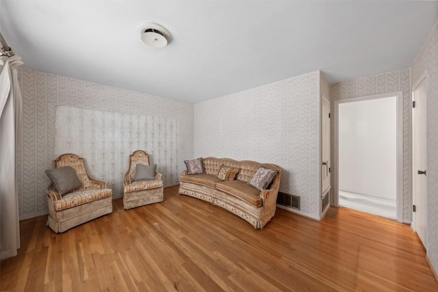 sitting room with visible vents, wood finished floors, and wallpapered walls