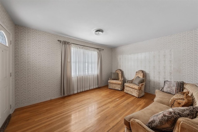 sitting room with wood finished floors and wallpapered walls
