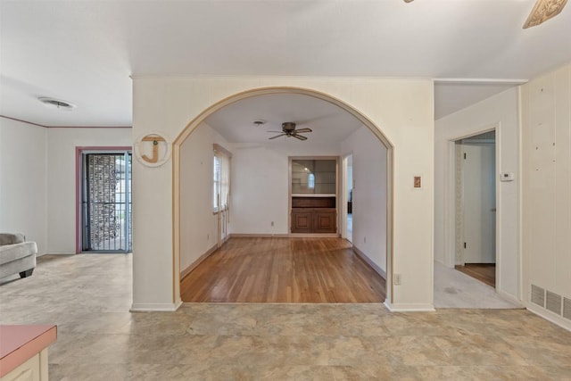 entryway with arched walkways, ceiling fan, visible vents, and baseboards