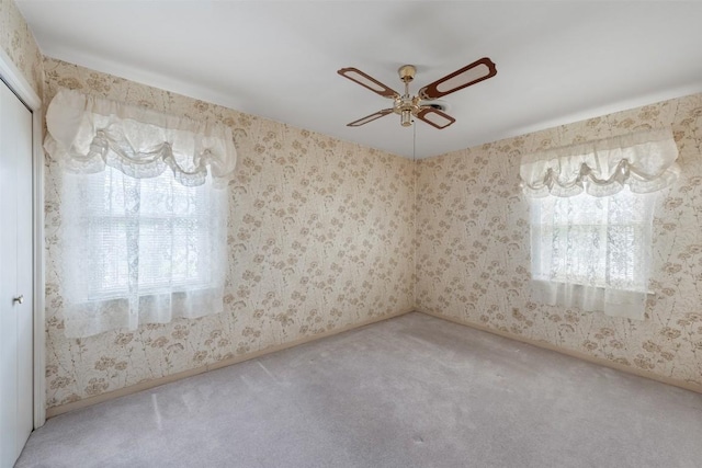 carpeted spare room with a ceiling fan