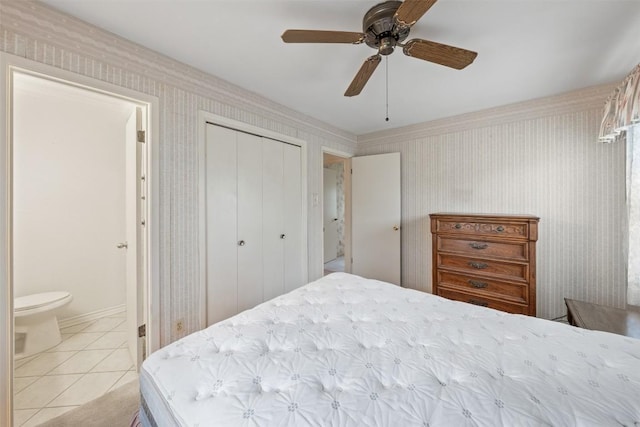 bedroom with light tile patterned floors, ceiling fan, a closet, and wallpapered walls