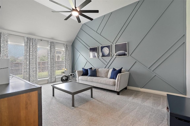 living room with carpet floors, a ceiling fan, a decorative wall, and vaulted ceiling