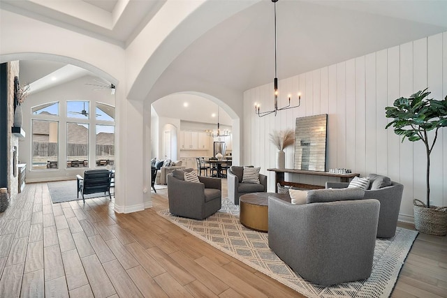 living area featuring arched walkways, a high ceiling, and light wood-style flooring
