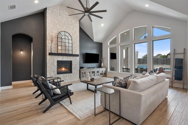 living room with visible vents, a ceiling fan, light wood finished floors, and a fireplace