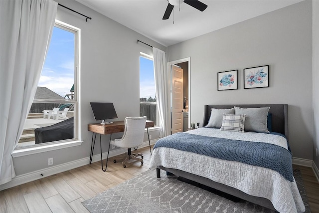 bedroom with baseboards, ceiling fan, wood finished floors, and ensuite bathroom