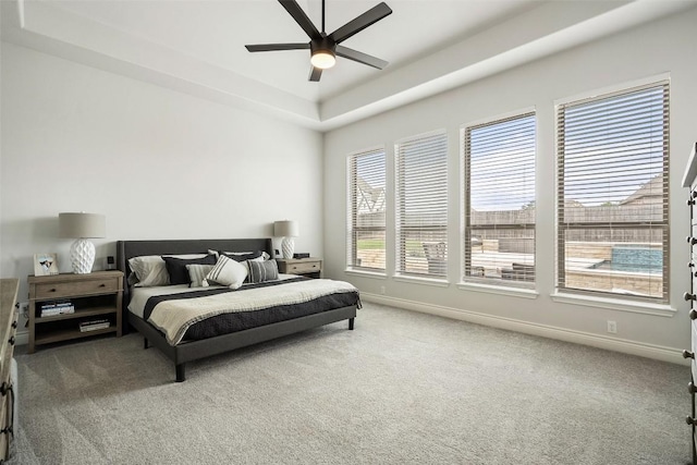 bedroom with carpet flooring, a ceiling fan, baseboards, and a tray ceiling