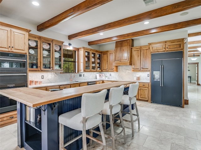 kitchen with visible vents, decorative backsplash, a breakfast bar area, recessed lighting, and built in fridge
