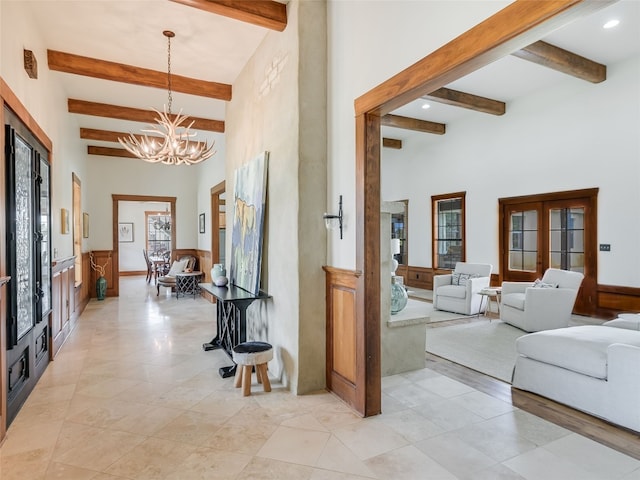 corridor featuring plenty of natural light, beamed ceiling, a chandelier, and a towering ceiling