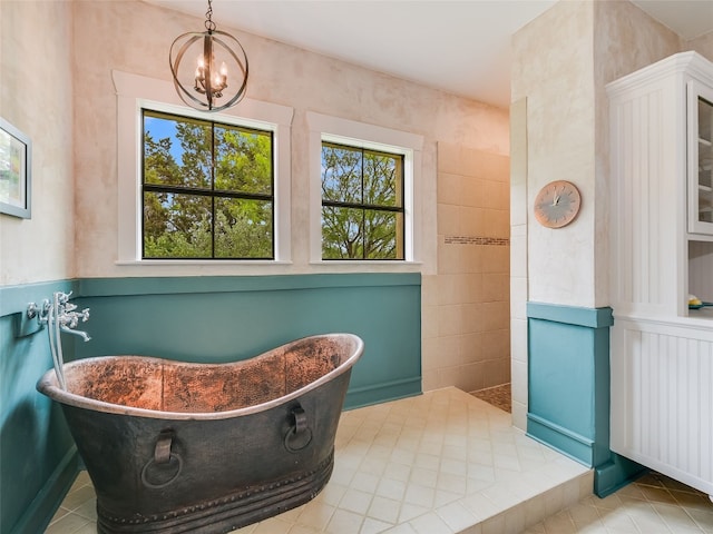 full bath featuring tile patterned flooring, a walk in shower, a freestanding bath, and an inviting chandelier