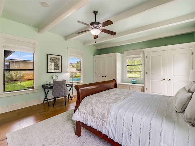 424 Hidden Creek Dr, Dripping Springs, TX 78620 - bedroom featuring beam ceiling, wood finished floors, two closets, and multiple windows