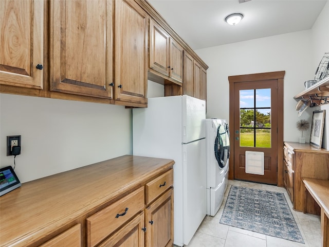 laundry room featuring cabinet space, light tile patterned flooring, and washer and clothes dryer