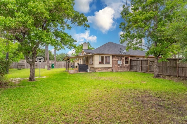 rear view of property with a patio, a fenced backyard, a chimney, brick siding, and a lawn