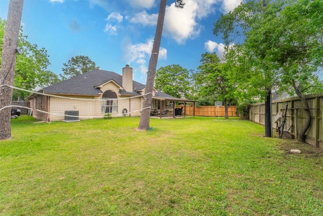 back of house with central AC, a fenced backyard, a chimney, a patio, and a yard