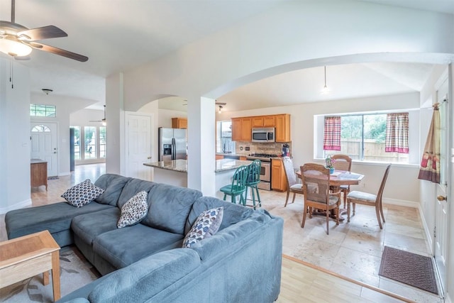 living area with baseboards, arched walkways, and ceiling fan