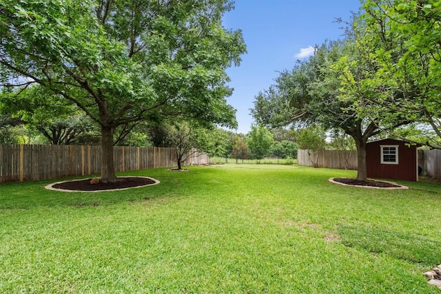 view of yard with a fenced backyard, a storage unit, and an outbuilding
