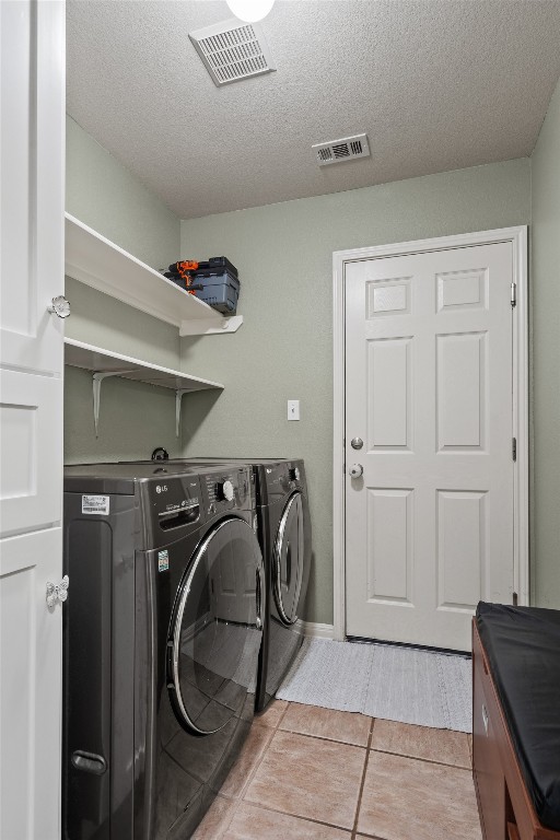 laundry room featuring washing machine and clothes dryer, laundry area, a textured ceiling, and visible vents